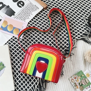 Close-up of rainbow crossbody bag with red heart detail and glossy patent leather finish