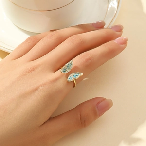 Gold butterfly ring with blue enamel wings and sparkling crystals on model's finger