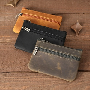 Trois porte-monnaie en cuir vintage marron et noir sur un fond en bois rustique