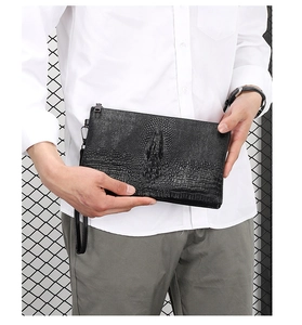 Detail of black faux leather men's clutch with 3D embossed crocodile texture and wrist strap