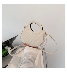Detail of white striped saddle bag with round handle and gold hardware accents
