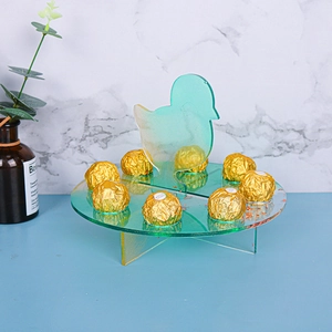 Detail of acrylic Christmas chick display stand holding gold foil chocolates on blue desk