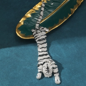 Detailed close-up of a tiger brooch with crystals and black enamel on a green ceramic leaf