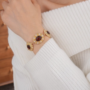 Detail of vintage gold bracelet with red oval gems and floral accents on model wrist