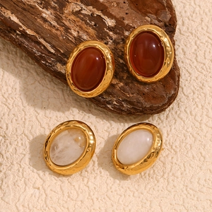 Detail of vintage 18K gold plated oval earrings with natural stone and hammered texture