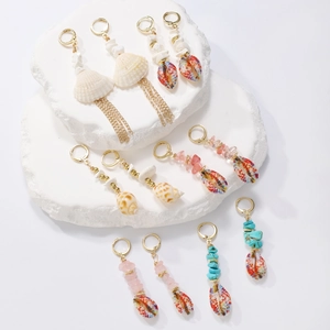 Detail of bohemian shell earrings with gold hoops and colorful gravel on stone pedestals