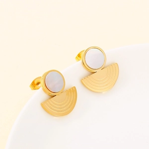 Macro shot of gold geometric earrings with white circular inlay on white ceramic plate