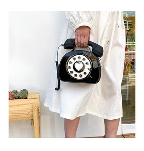 Close-up of a creative black telephone-shaped handbag with a heart dial and handset handle