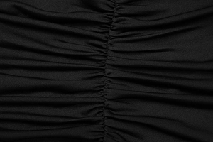 Dettaglio macro del tessuto arricciato nero su un abito aderente estivo con scollo all'americana
