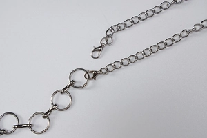 Detail van de zilveren metalen ketting en de karabijnsluiting op de jurk met uitsparing