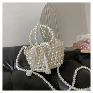 Détail du sac à main en perles blanches tressées avec un grand nœud en satin blanc