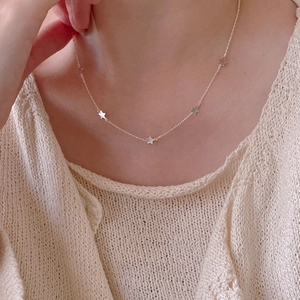 Close-up of 925 sterling silver necklace featuring five delicate star pendants on model