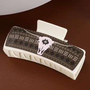 Detail of large cream faux leather hair claw clip featuring tribal bull skull pattern