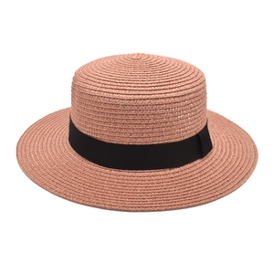 Detailed texture of a vintage brick red flat top straw sun hat with black ribbon