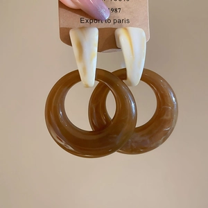 Close-up of brown resin hoop earrings with marble texture detail on elegant display card
