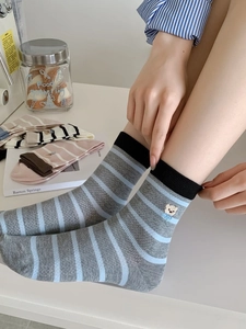 Gros plan de chaussettes rayées gris et bleu en coton avec broderie ours et bords côtelés
