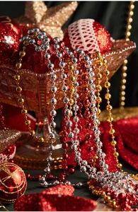 Detail of red and gold faceted star beads draped over a crystal bowl for Christmas decor