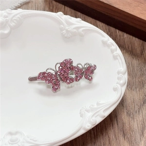Detailed view of silver hair clip with double pink rhinestones on white embossed plate