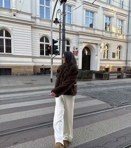 Style de rue d'une veste courte en fausse fourrure marron avec revers sur fond urbain