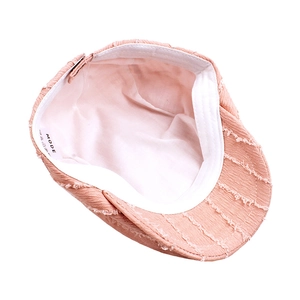 Détail de l'intérieur d'un béret rose avec coutures effilochées et étiquette MODE