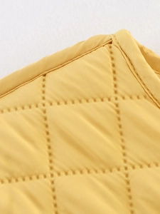 Détail de la veste matelassée jaune montrant les coutures précises et la texture du tissu