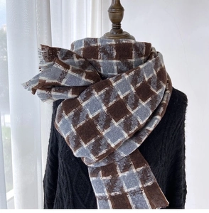 Detailed view of heavy houndstooth scarf texture and fringe on a black cable knit sweater