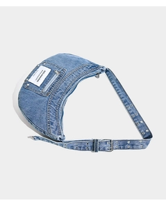 Detail of blue washed denim crescent bag with metal eyelets on strap and brand tag