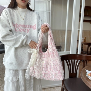 Close-up of pink lace shoulder bag with a large white decorative bow detail