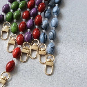 Close-up of colorful acrylic resin bead chains with gold lobster clasps and marble textures
