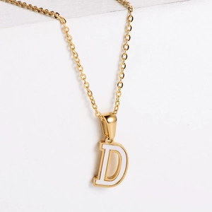 Macro shot of 18k gold necklace featuring a letter D pendant with white shell inlay