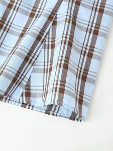 Detailed close-up of light blue and brown plaid pattern with precise stitching on poplin fabric