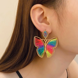 Detail of colorful woven butterfly earrings with gold frame in Bohemian style