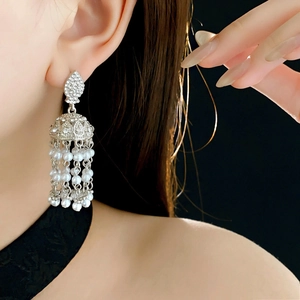Macro shot of silver pearl tassel earrings with rhinestones on a model in dark setting