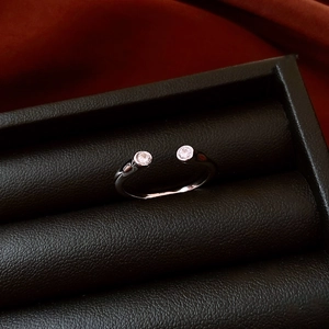 Detail shot of a silver adjustable star ring with two clear circular gems in a gift box