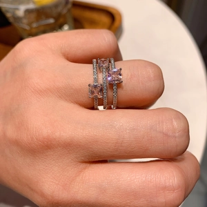 Close-up of three-layer silver ring set with square pink gemstones and pave diamonds