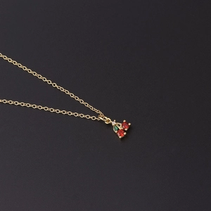 Macro shot of gold cherry pendant necklace with red and green cubic zirconia stones