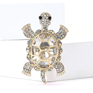 Detailed view of turtle brooch featuring clear crystals and rhinestones in gold finish