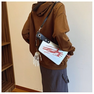 Creative cleaver shaped crossbody bag with blood splatter and bone hand charm on a model