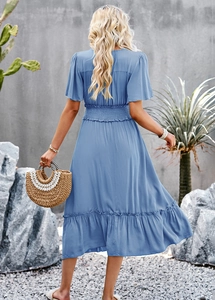 Detail of the back view showing elastic waist and ruffled hem of blue V-neck dress