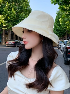 Side view of woman wearing a cream pleated sun hat for summer outdoor protection