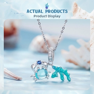 Detail of silver crab charm with blue shell and coral element in a nautical theme