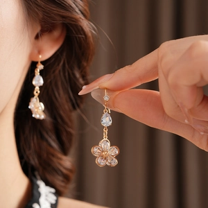 Detail of gold flower earrings with teardrop zircon crystals on model for a luxury look