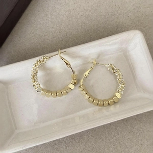 Detailed view of gold hoop earrings featuring cubic beads and sparkling rhinestones
