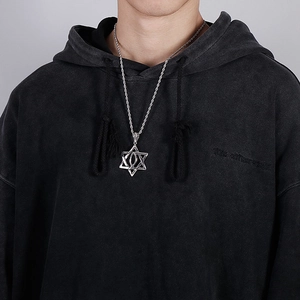 Close-up of a silver hexagram pendant on a rope chain worn by a model on grey background