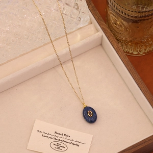 Detail of blue oval gemstone necklace with gold chain inside a luxury jewelry box