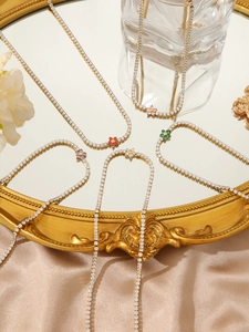 Macro view of dainty gold necklaces with colorful zircon flower pendants on a mirror
