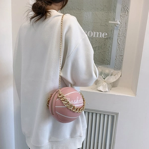Pink basketball shaped leather chain bag for women worn by model in a street style view
