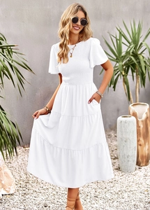 Detail view of white smocked dress with ruffled sleeves and tiered skirt texture