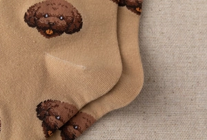 Close-up of knit fabric and heel stitching on beige socks with brown puppy patterns