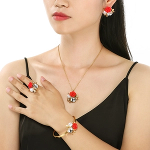 Close-up of gold jewelry set with red roses and white pearls on a female model